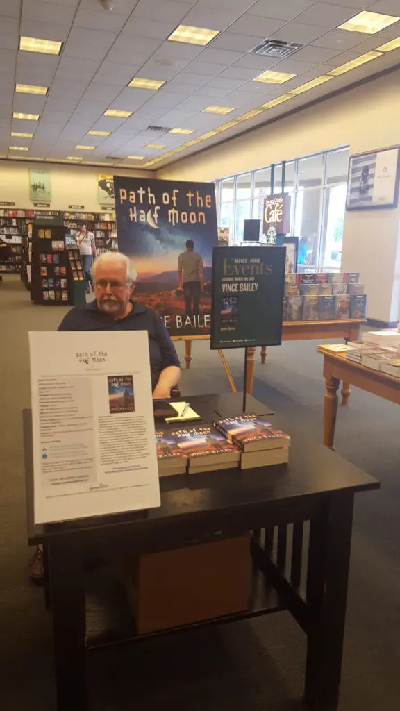 A man sitting at a table with several books.